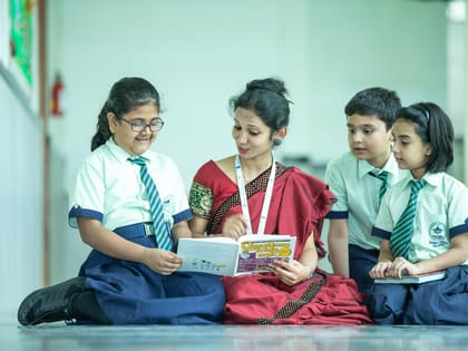 A teacher reading with three pupils in a school corridor