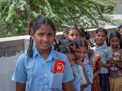 Pupils in blue check uniform outside their classroom